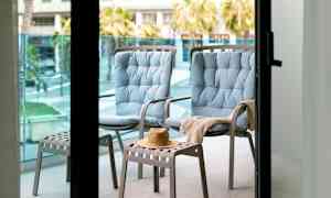 Två blåa sittstolar och en pall med en hatt på en balkong. (AI-genererad text)