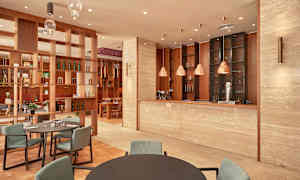 Interiör av en restaurang med modern inredning, inklusive bord, stolar och en bardisk. (AI-genererad text)