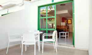 Uteplats med vita möbler som vetter mot en grön ramskogsdörr med utsikt in i en lägenhet. (AI-genererad text)