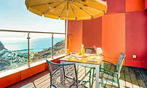 En terrass med bord, stolar och parasoll med utsikt över havet. (AI-genererad text)