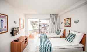 Hotellrum med två enkelsängar, balkong med utsikt över omgivningen. (AI-genererad text)