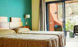 Hotellrum med två enkelsängar och en balkong med utsikt. (AI-genererad text)