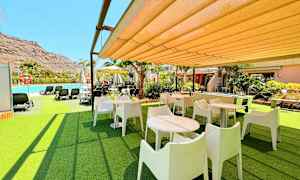 Utomhusområde med bord, stolar och närliggande pool. (AI-genererad text)