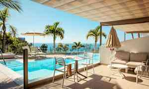 En uteplats med en pool och utsikt över havet, omgiven av palmträd. (AI-genererad text)