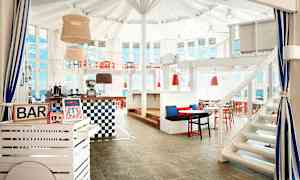 En inomhusbar med vita och röda möbler samt stora fönster. (AI-genererad text)