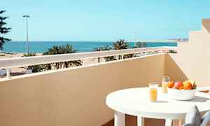 Balkong med havsutsikt, ett bord med fruktskål och glas med juice. (AI-genererad text)