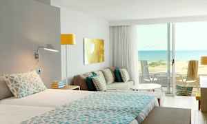 Hotellrum med utsikt över en sandstrand och havet. (AI-genererad text)