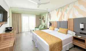 Ett hotellrum med två sängar, en soffa och en dekorativ väggdesign. (AI-genererad text)