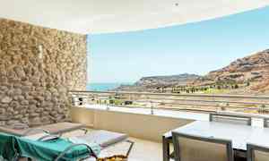 Terrass med solstolar och utsikt över havet och en bergig landskap. (AI-genererad text)