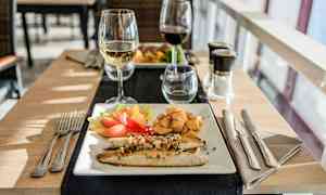 En tallrik med fisk, grönsaker och potatis, samt ett glas vitt vin. (AI-genererad text)