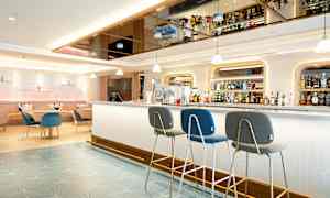 Modern hotellbar med sittplatser och hyllor fyllda med flaskor. (AI-genererad text)