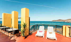 En terrass med utsikt över havet, utrustad med solstolar, bord och stolar. (AI-genererad text)