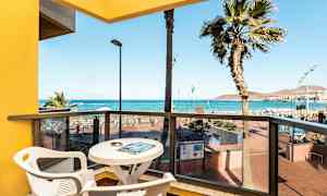 Utsikt från en balkong med bord och stolar mot havet och stranden. (AI-genererad text)