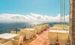 Terrass med bord och stolar vid havet. (AI-genererad text)