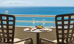 Två tallrikar med mat och två glas med dryck på ett bord med havsutsikt. (AI-genererad text)