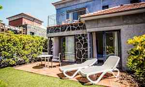 Bild av en terrass med solsängar och sittmöbler vid ett hus. (AI-genererad text)