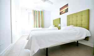 Ett rum med två enkelsängar med grön stoppad huvudgavel. (AI-genererad text)