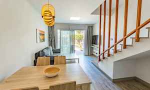 Ett vardagsrum med bord, stolar, en soffgrupp och en trappa. (AI-genererad text)