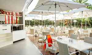 Utomhus servering med bord och stolar under parasoller. (AI-genererad text)