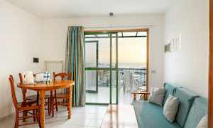 Ett rum med matbord och stolar, soffa och glasdörr till en balkong. (AI-genererad text)