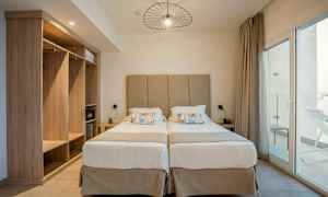 Två enkelsängar med en beige huvudgavel och nattduksbord på varje sida. (AI-genererad text)