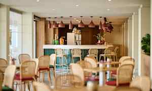 En ljus och modern inomhusbar med barstolar och bord placerade runt omkring. (AI-genererad text)