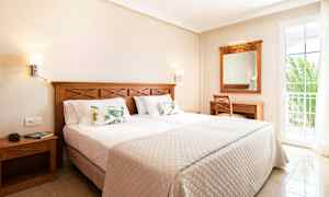 Ett hotellrum med en dubbelsäng, träinredning och en balkongdörr. (AI-genererad text)