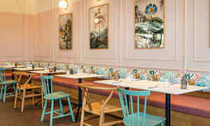 En restaurang med bord och stolar, bilder på väggen och mjuka soffor längs väggen. (AI-genererad text)