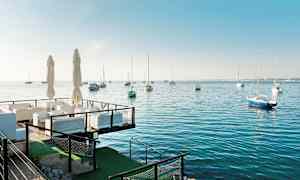 Uteservering vid havet med segelbåtar på vattnet. (AI-genererad text)