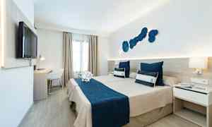 Hotellrum med två sängar och marin-tema, blå sängkläder och prydnadskuddar. (AI-genererad text)