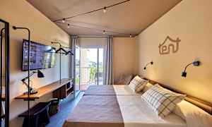 Hotellrum med två enkelsängar, arbetsbord med lampa och TV, samt balkong med utsikt. (AI-genererad text)