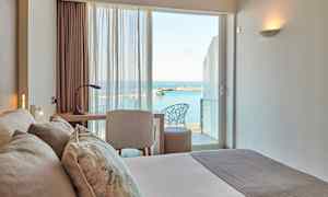 Ett hotellrum med utsikt över havet genom fönstret. (AI-genererad text)