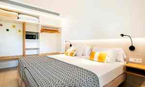 Hotellrum med en dubbelsäng, sänglampor, och en garderob. (AI-genererad text)