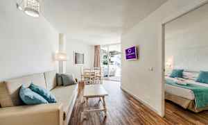 Bild av ett hotellrum med vardagsrum, soffa, matbord och anslutande sovrum. (AI-genererad text)