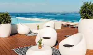 Loungeområde vid en pool med moderna möbler och utsikt över havet. (AI-genererad text)