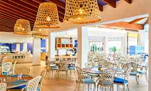 Ljus och luftig restaurang med elegant möblemang och stora korglampor. (AI-genererad text)