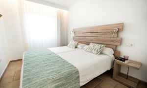 Två enkelsängar med gröna sängöverkast i ett ljust rum. (AI-genererad text)