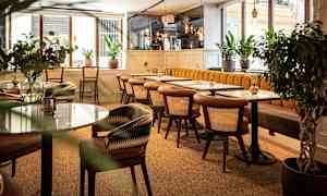 Ett modernt kafé med trästolar och marmorbord, omgivna av gröna växter. (AI-genererad text)