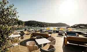 Uteservering med utsikt över havet och omgivande berg (AI-genererad text)