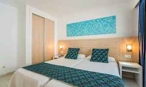 Ett hotellrum med två enkelsängar med blå detaljer. (AI-genererad text)