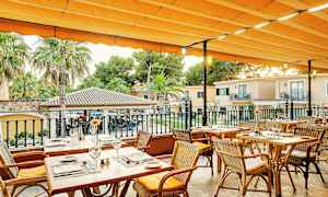 Utomhusterrass med dukade träbord och stolar under en orange markis. (AI-genererad text)