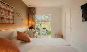 Ett hotellrum med två sängar, dekorativ väggbonad, och en terrass med utsikt över grönområde. (AI-genererad text)