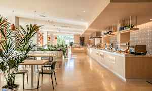 Ljust och modernt matområde med bord, stolar och bufféfad. (AI-genererad text)