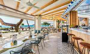 En utomhusbar med sittplatser, havet synligt i bakgrunden. (AI-genererad text)