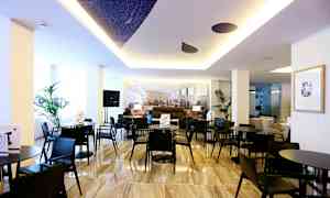 Ett modernt interiörutrymme med svarta bord och stolar, dekorativa växter och en ljus atmosfär. (AI-genererad text)