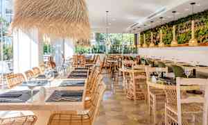 Restaurang med träbord, rottingstolar och dekorativa ljusarmaturer. (AI-genererad text)