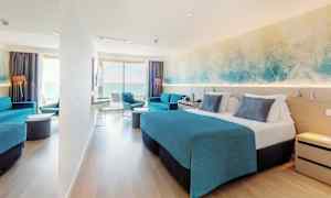 Ett hotellrum med dubbelsäng, blå inredning och en sittgrupp. Ett stort fönster ger utsikt över havet. (AI-genererad text)