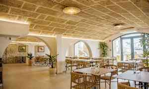 Interiör av en restaurang med stenvalv, moderna möbler och dekorativa växter. (AI-genererad text)