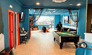 Ett inomhusrum med en biljardbord, sittplatser och dekorationer i färgglada detaljer. (AI-genererad text)