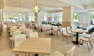 En modern och ljus inomhusrestaurang med trämöbler och dekorativa lampor. (AI-genererad text)